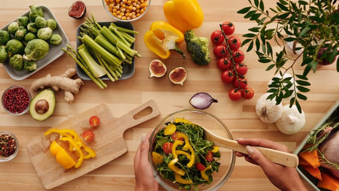 Top view of fresh vegetables and salad preparation on a wooden table, perfect for healthy eating concepts.